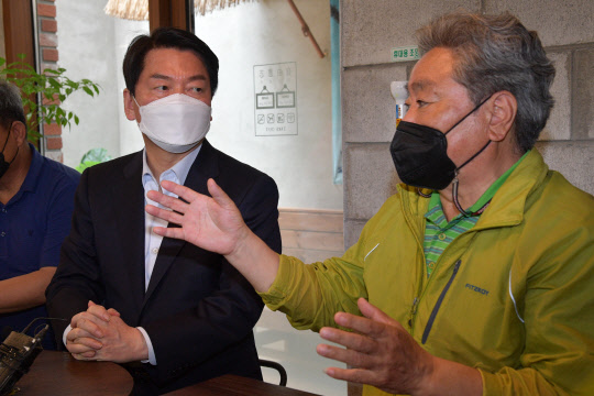 6·1 국회의원 재·보궐선거 경기 성남 분당갑에 국민의힘 후보로 출마한 안철수(왼쪽) 전 대통령직인수위원장이 지난 5월13일 오전 경기도 성남시 분당구 대장동의 한 카페에서 열린 대장동 원주민과의 간담회에서 참석자들의 발언을 듣고 있다.<공동취재·연합뉴스>